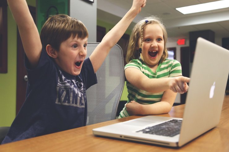 Zwei Kinder jubeln vor einem Laptop